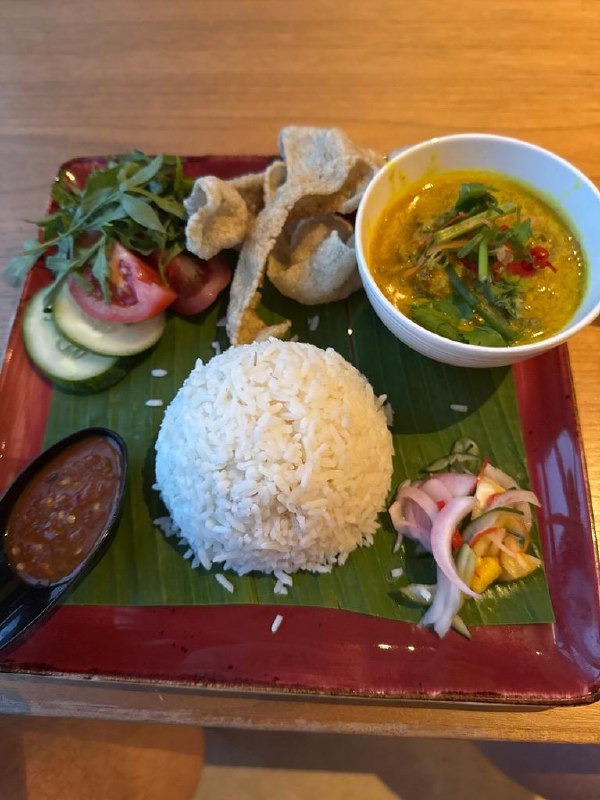 Nasi padang at the hotel: rice, curry, sambal, acar, and crackers on a banana leaf.