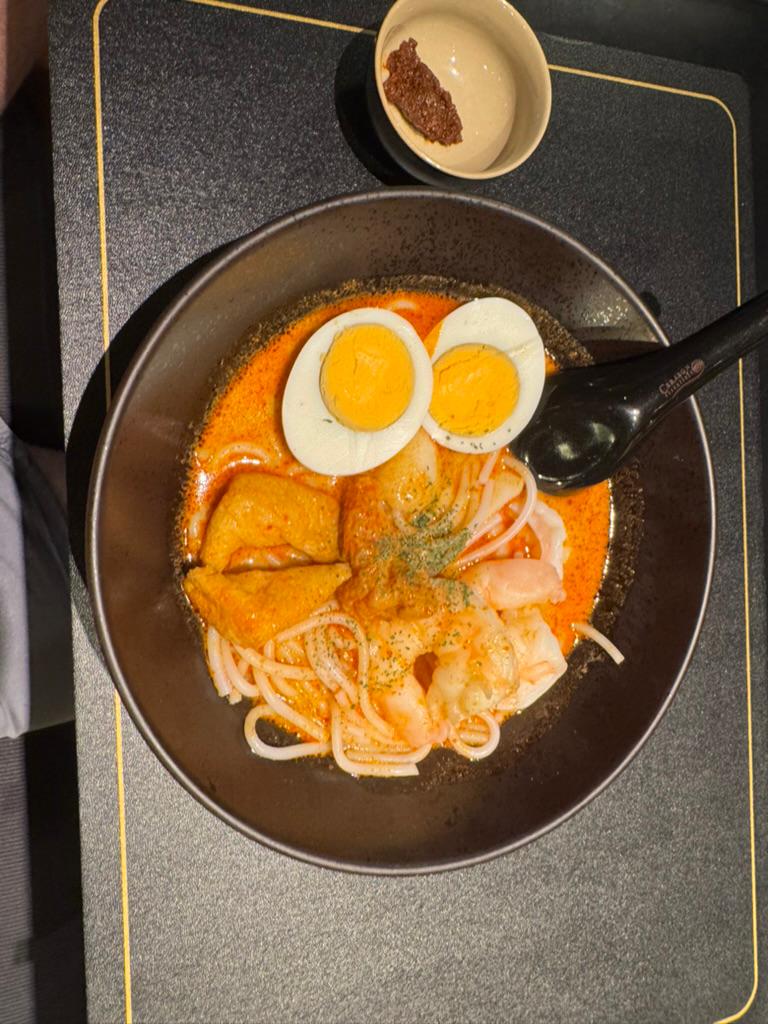 Singapore laksa with egg, fish cake, and prawn, sambal on the side.
